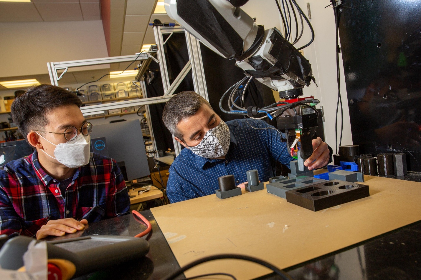 two individuals working with a robot arm two individuals working with a robot arm